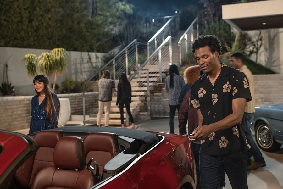 2024 Mustang® GT convertible and a first-gen Mustang coupe parked in a driveway with people nearby