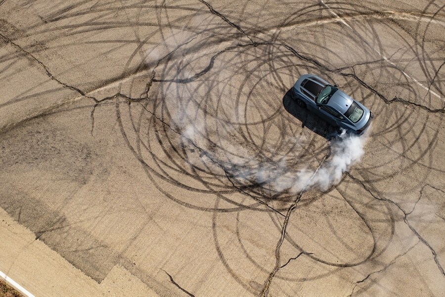 2024 Ford Mustang® coupe with stripes and a driver performing burnouts on a closed course