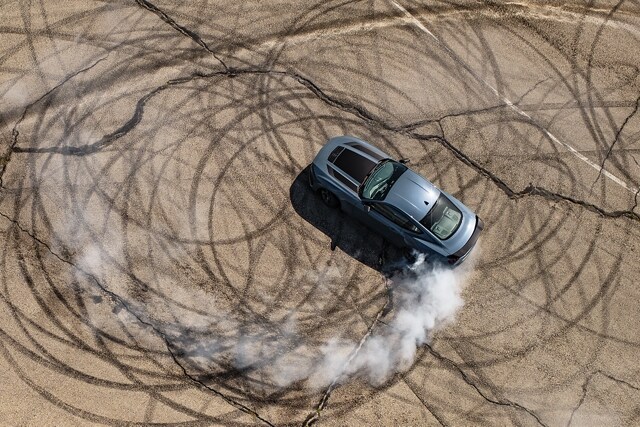 2024 Ford Mustang® coupe with stripes and a driver performing burnouts on a closed course