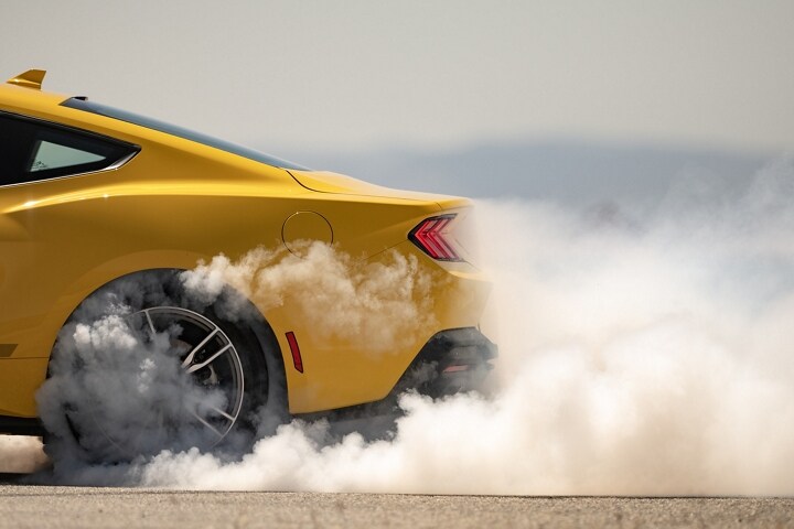 2024 Ford Mustang® EcoBoost® coupe in Yellow Splash Metallic Tri-coat with driver doing burnouts