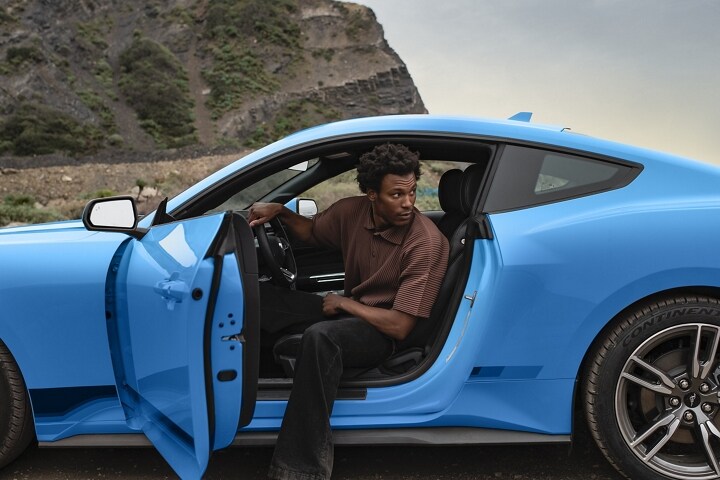 Person exiting a 2024 Mustang® EcoBoost® coupe in Grabber Blue Metallic