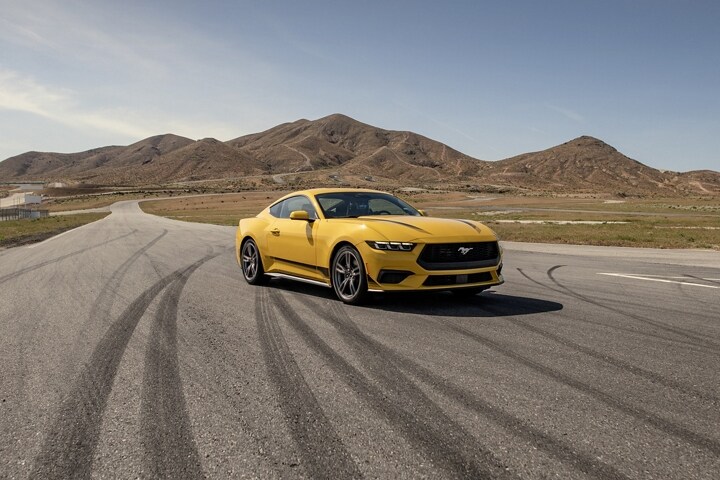 2024 Ford Mustang® EcoBoost® coupe in Yellow Splash Metallic Tri-coat parked on a racecourse