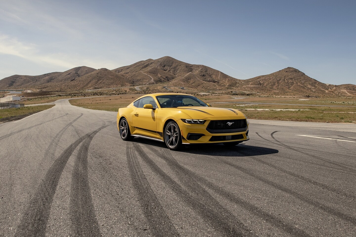 2024 Ford Mustang® EcoBoost® coupe with available Wheel and Stripe package parked on a racecourse