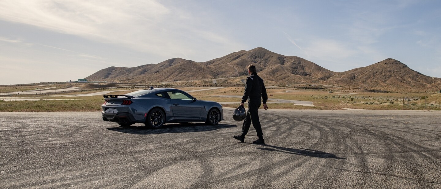 Person approaching a 2024 Ford Mustang® Dark Horse™ coupe parked on a closed course