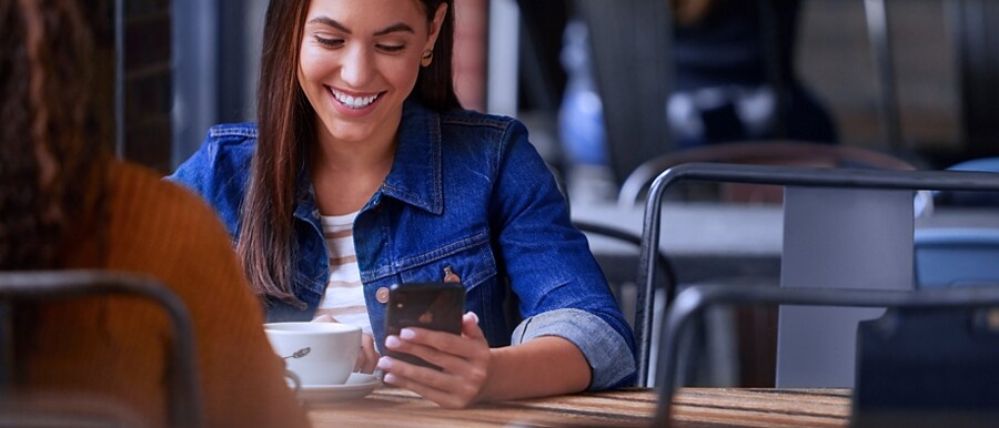 Two people sitting at a table with one using a smartphone