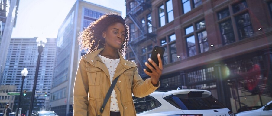 Person walking down a city street using a smartphone
