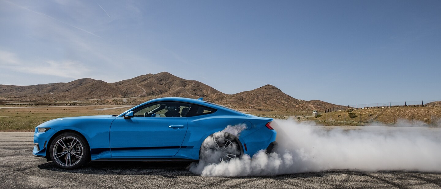2025 Ford MustangÃÂ® EcoBoostÃÂ® coupe in with a driver doing burnouts on a closed course
