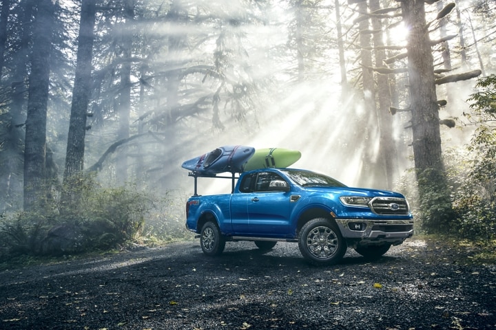 2021 Ford Ranger in Lightning Blue on forest road with kayaks on optional bed mounted rack accessory