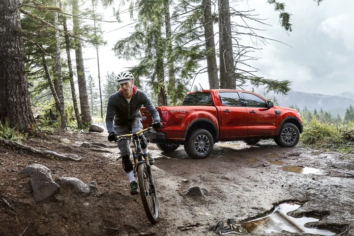 2021 Ford Ranger X L T in Race Red in the outdoors with mountain biker