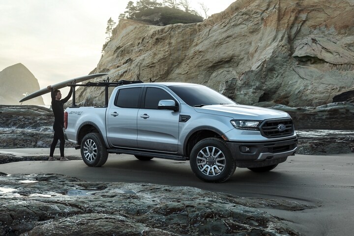 Se muestra la Ford Ranger 2023 con accesorio de rieles opcional montado en la plataforma a la orilla del mar con surfista
