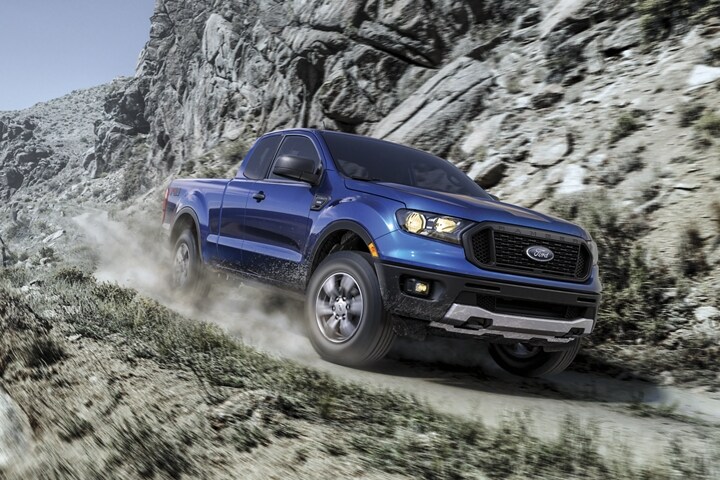 Ford Ranger 2023 en Velocity Blue andando cuesta abajo por un camino sin pavimentar al lado de la montaña