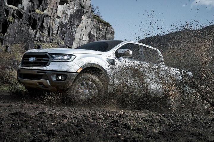Ford Ranger LARIAT SuperCrew 2023 subiendo una colina entre el barro y el agua