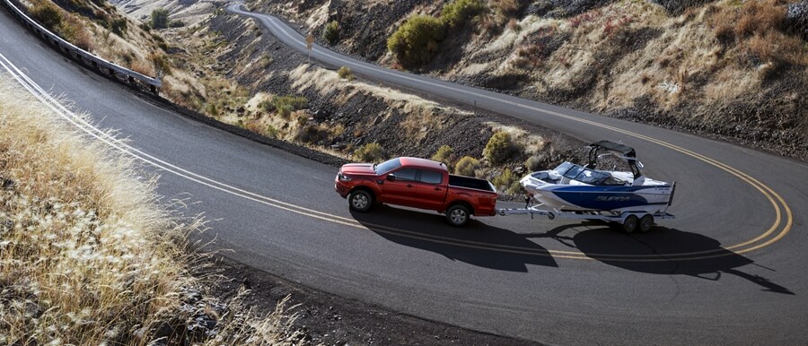 Una Ford Ranger® XLT 2023 en race red remolcando un bote por una carretera