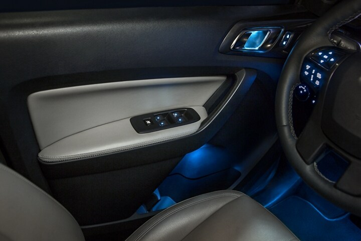 Se muestra panel de la puerta de la Ford Ranger LARIAT 2023 con detalles en Medium Gray e iluminación ambiental