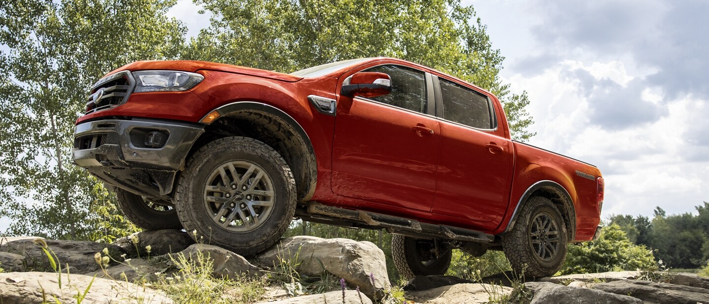 Una Ford Ranger 2023 en Race Red con el Paquete para Todo Terreno Tremor® circulando por un camino rocoso