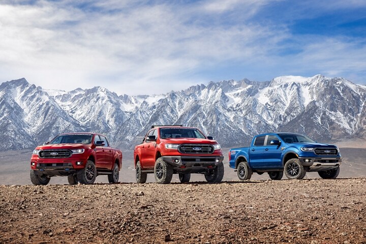 Varios modelos Ford Ranger 2023 con Paquetes de Piezas de Desempeño Ford estacionados en la tierra enfrente de un paisaje montañoso