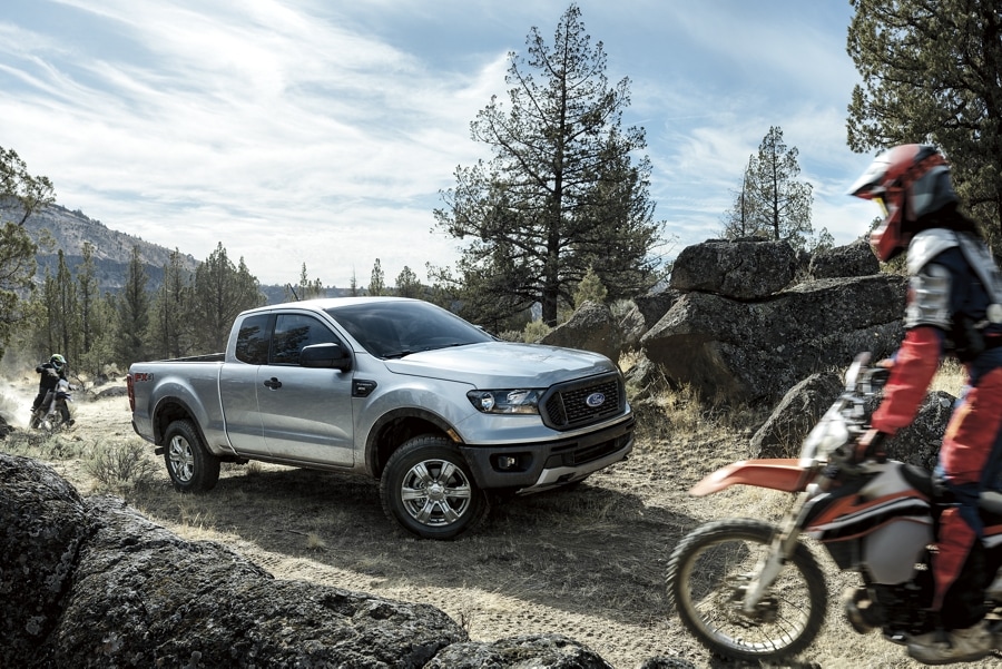 2023 Ford Ranger shown in Iconic Silver being driven off-road with dirt bikes to the front and rear