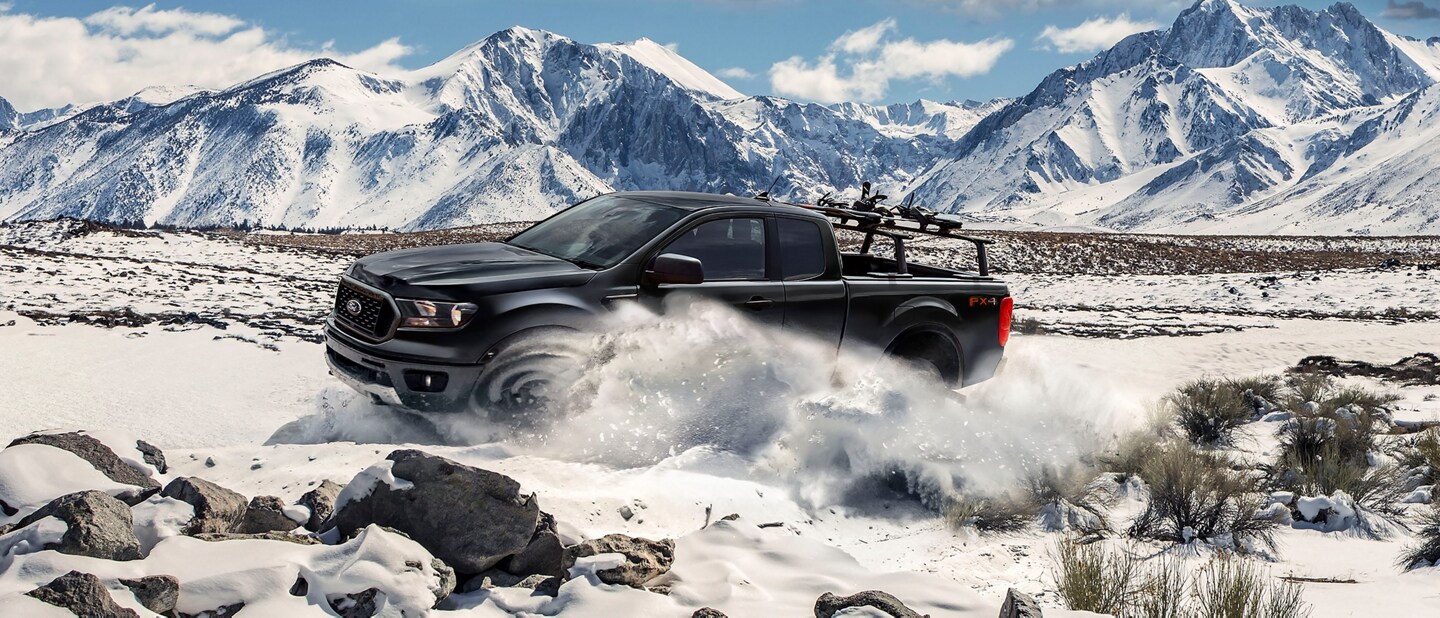 Una Ford Ranger® 2023 en shadow black circulando por la nieve con montañas de fondo