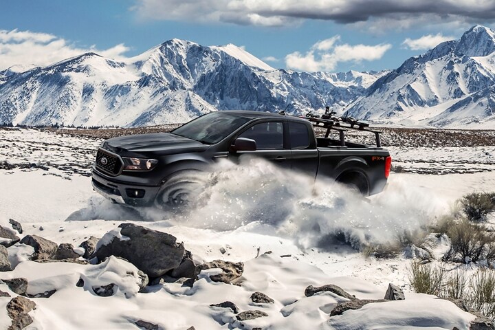 Ford Ranger 2023 en terreno montañoso cubierto de nieve con accesorio de rieles opcional montado en la plataforma.