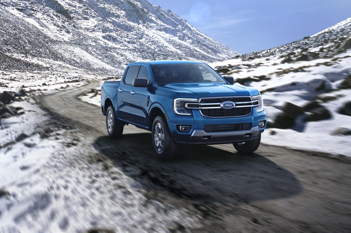 A 2024 Ford Ranger® is being driven on a road along snowy mountains