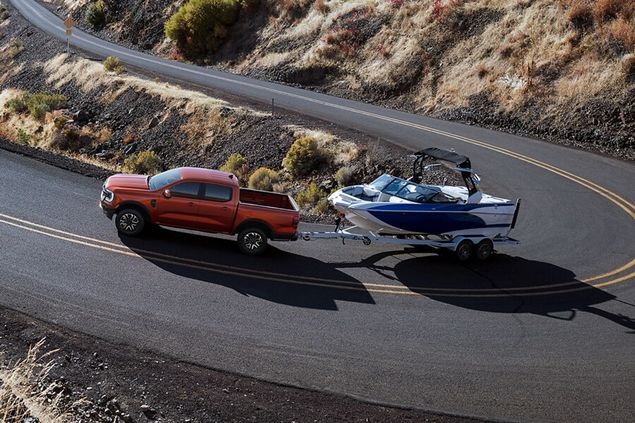 A 2024 Ford Ranger® is towing a boat on a road through the mountains