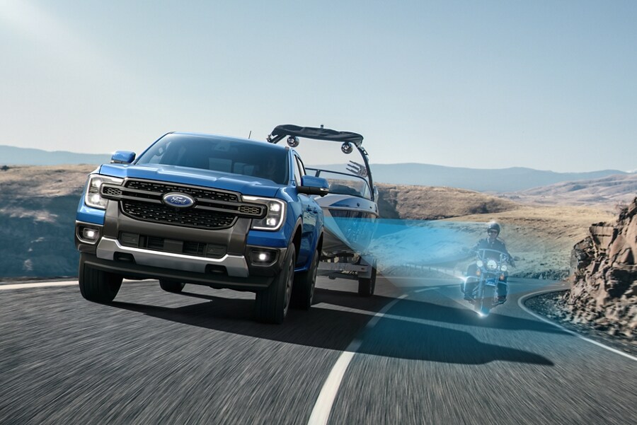 A 2024 Ford Ranger® towing a boat on a highway engaged with BLIS® sensing a motorcyclist