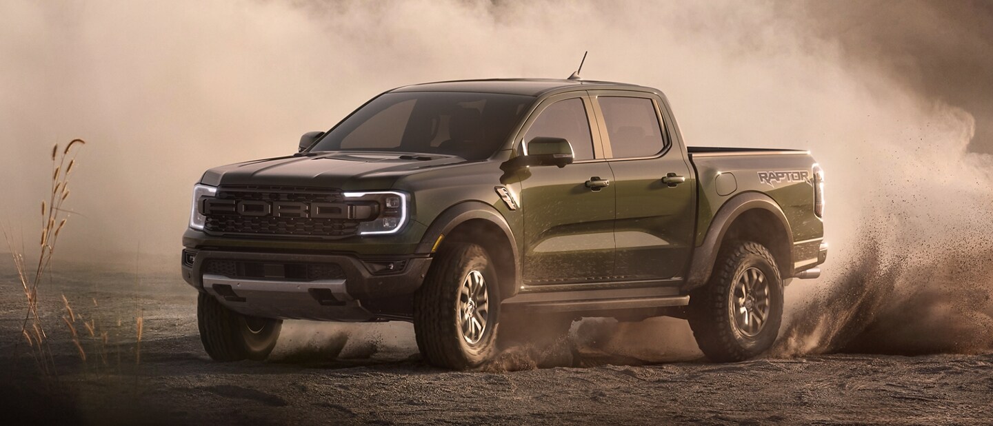 A 2024 Ford Ranger® Raptor® in Shelter Green is accelerating through sand