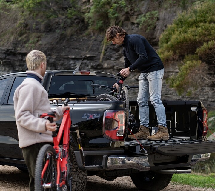 Two people are loading gear into the bed of a 2024 Ford Ranger® in Agate Black