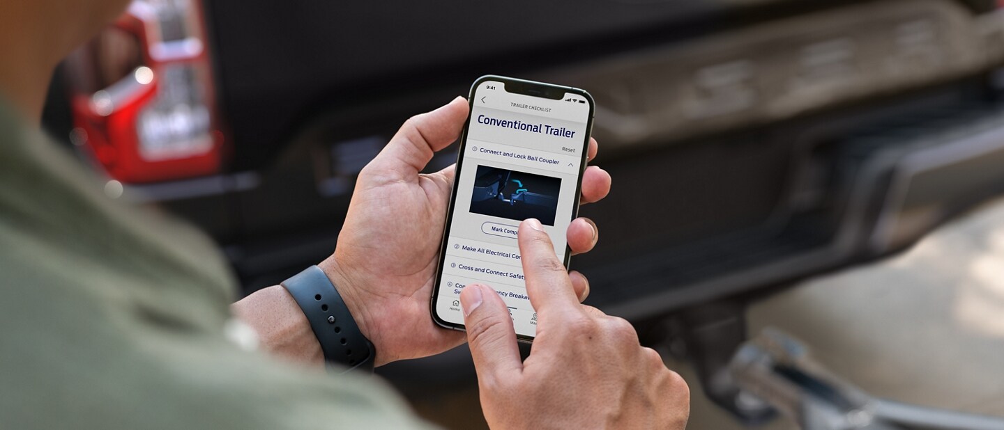 A person's hand is holding a cellular phone with Trailer Light Check Function being performed