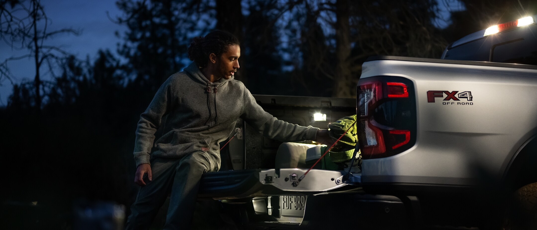 A person working in the truck bed of a 2024 Ford Ranger® lit up at dusk by LED Bed Lighting