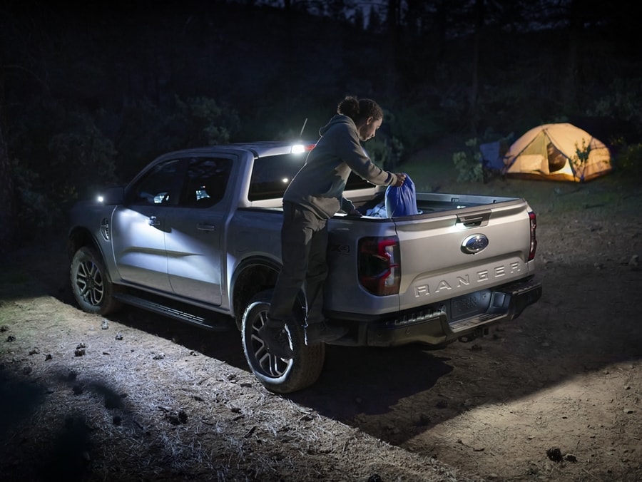 A person accesses camping gear in the bed of a 2024 Ford Ranger® in Iconic Silver at dusk