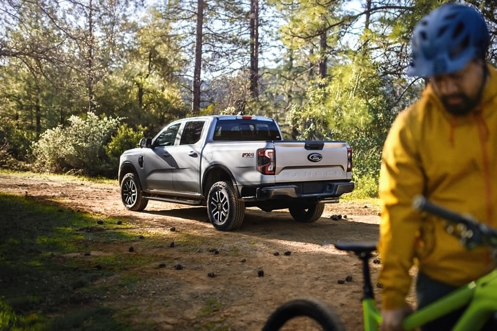 A 2024 Ford Ranger® LARIAT® parked on a dirt road with a person on a mountain bike