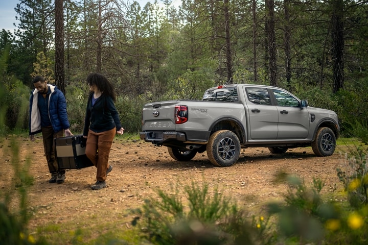 A 2024 Ford Ranger® in Oxford White is parked on a sandy road with two people unloading gear
