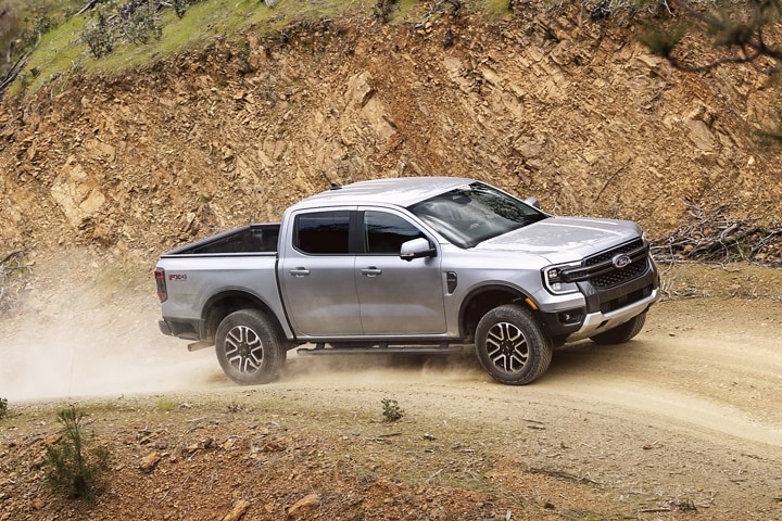 A 2024 Ford Ranger® in Iconic Silver is being driven up a sandy hill