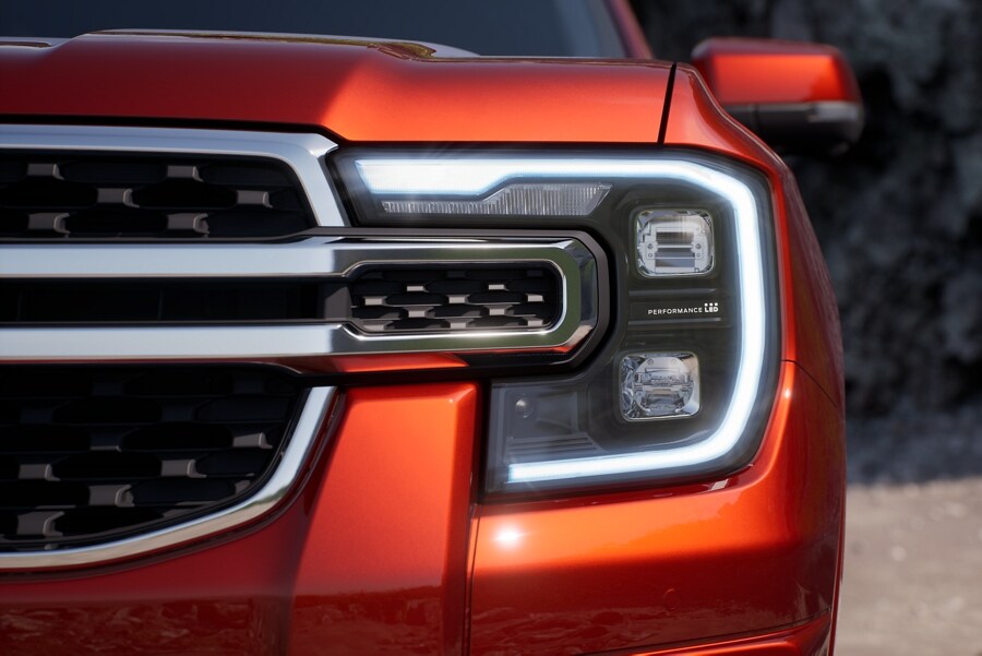 A 2024 Ford Ranger® LARIAT® in Hot Pepper Red is parked with a close-up of the LED Project Headlamps