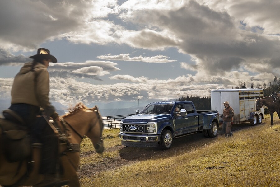 Un hombre caminando hacia una Ford Super Duty® F-450® King Ranch® DRW 2023 enganchada a un remolque para caballos