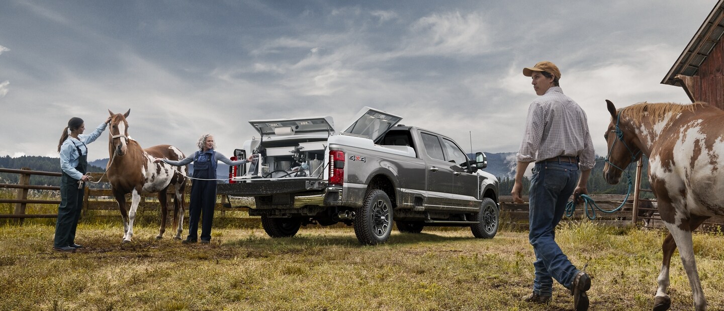 Man walking with a horse toward two women standing at the rear of a 2023 Ford Super Duty® F-250® Platinum pickup