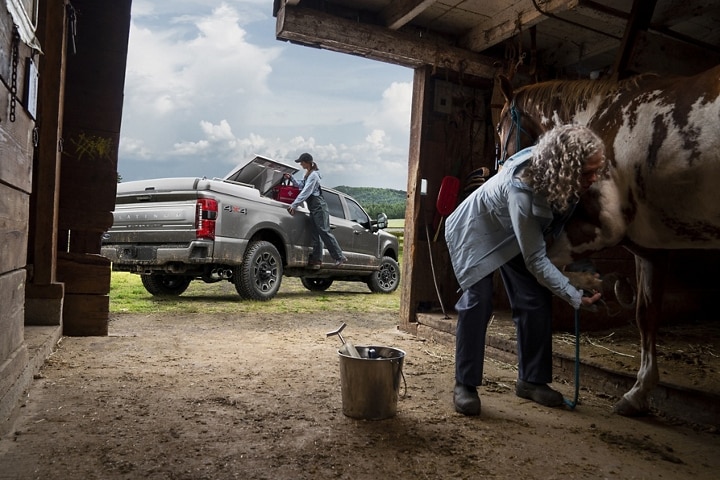 Woman using the box side step to load items into the bed of a 2023 Ford Super Duty® pickup