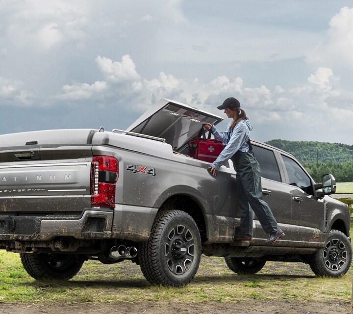 Woman using the box side step to load items into the bed of a 2023 Ford Super Duty® pickup