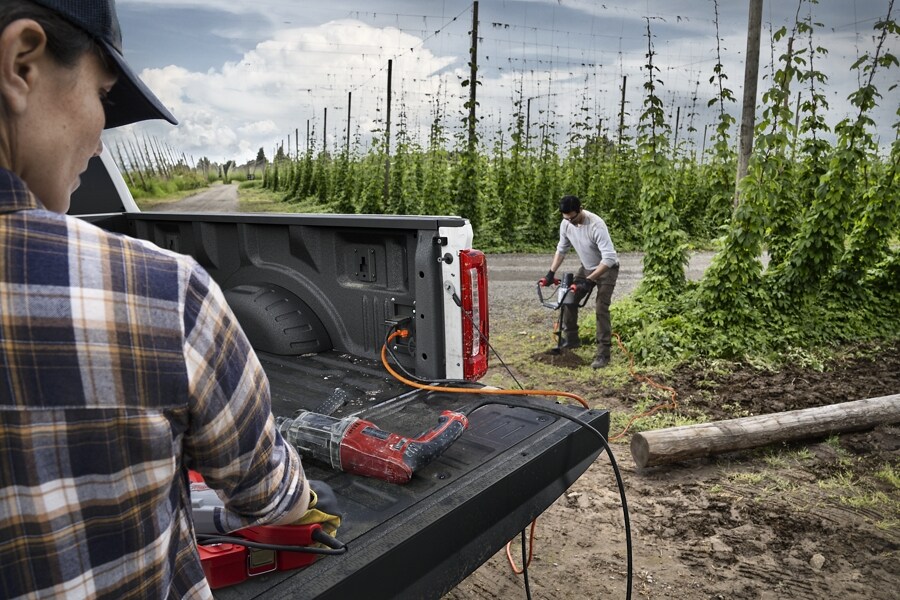 Extension cords plugged into the Pro Power Onboard feature with a person using an auger in the background