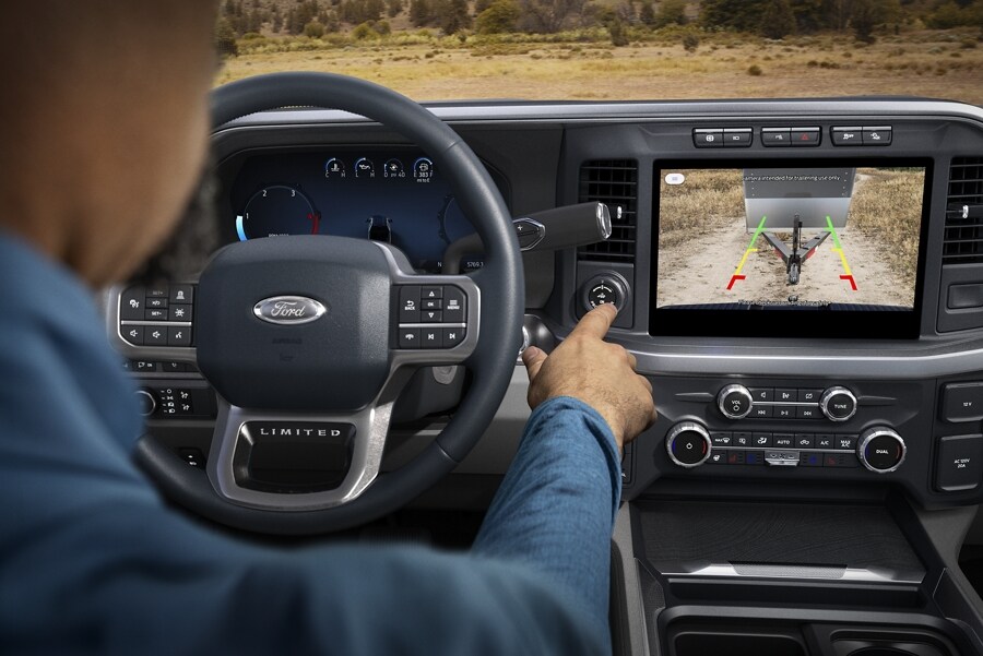 Close-up of the center display screen and a person pressing the Pro Trailer Hitch Assist button