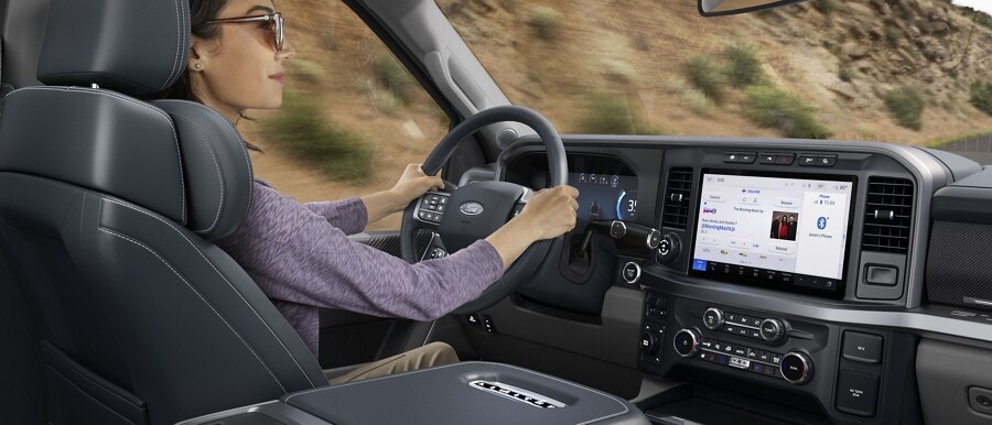 Woman driving with the navigation and music split screen shown on the 12-inch center display