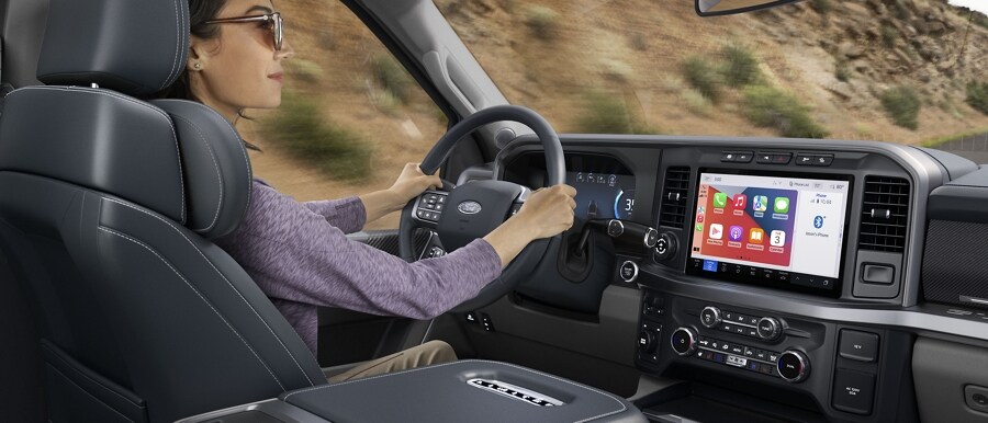 Woman driving with the 12-inch display screen showing Apple CarPlay Applications