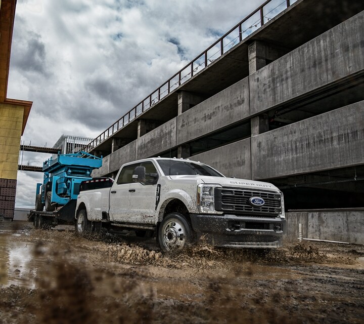 2023 Ford Super Duty® F-450® Super Crew Cab pulling a hydraulic lift on trailer through muddy water