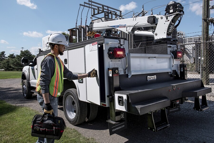 Utility worker standing next to a 2024 Ford Super Duty® F-550® Chassis Cab utility upfit