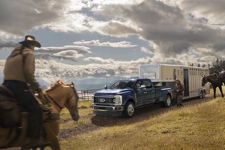 A man riding a horse toward a 2024 Ford Super Duty® F-450® King Ranch® DRW pickup hitched to a horse trailer