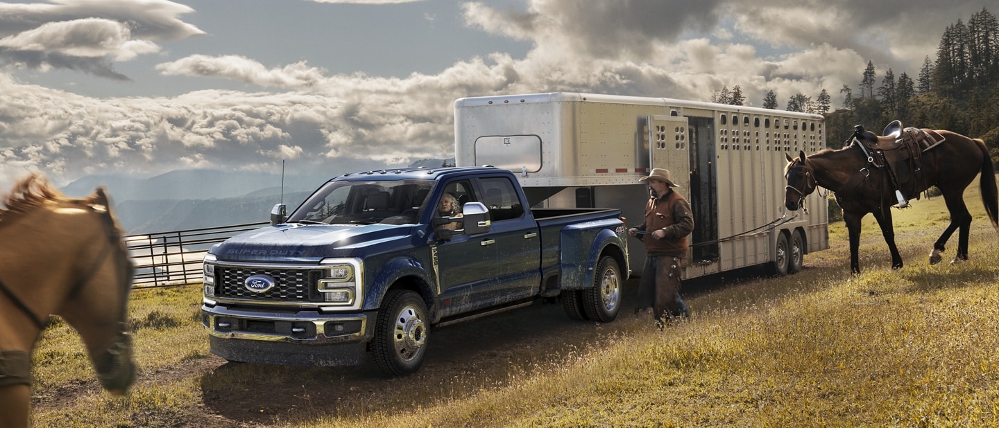 A man riding a horse toward a 2024 Ford Super Duty® F-450® King Ranch® DRW model hitched to a horse trailer