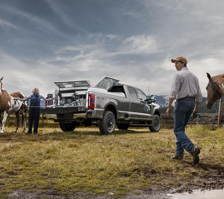 Man walking a horse toward two women standing near a 2024 Ford Super Duty® F-250® Platinum model with the tailgate down