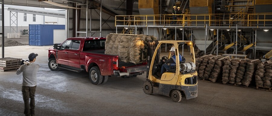 Man watching a hi-low load a crate into the bed of a Super Duty® pickup
