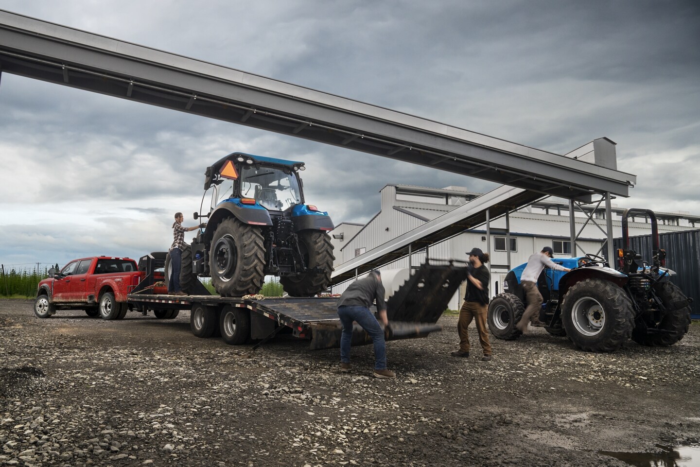  2024 Ford Super Duty F-350 XL in Race Red with a trailer attached to the back that is loaded with a tractor parked in construction zone.